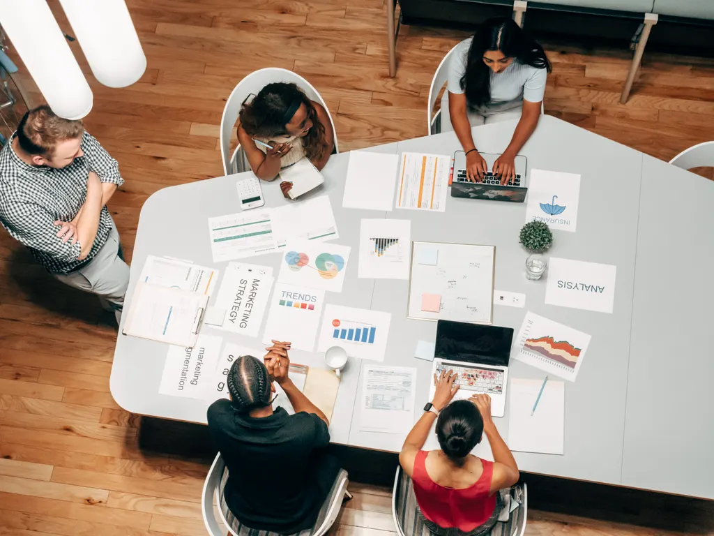 Overhead view of a team around a table covered with marketing strategy documents and charts